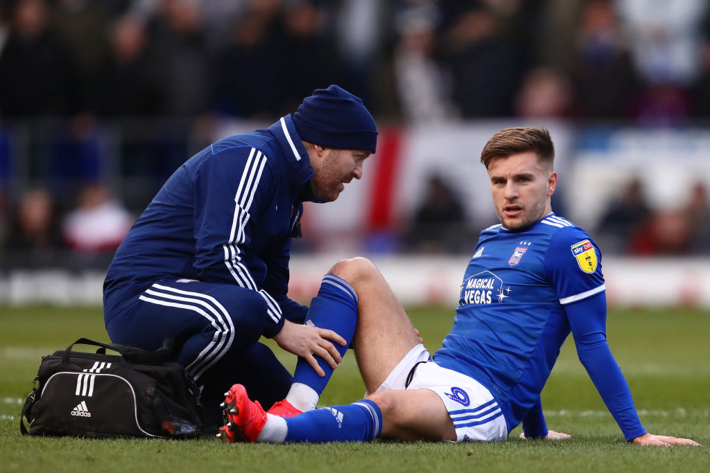 Luke Garbutt of Ipswich Town receives treatment before being...
