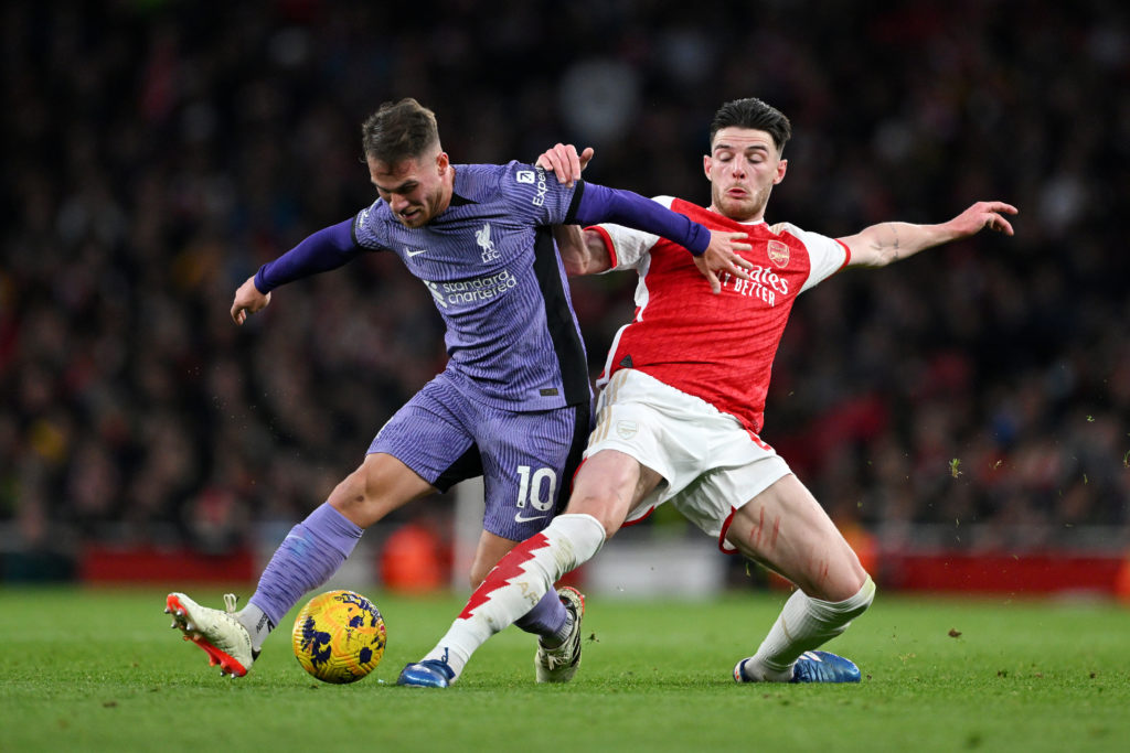 Alexis Mac Allister of Liverpool runs with the ball whilst under pressure from Declan Rice of Arsenal during the Premier League match between Arsen...