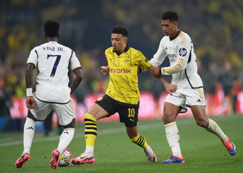 Jadon Sancho of Borussia Dortmund is challenged by Jude Bellingham and Vinicius Junior of Real Madrid  during the UEFA Champions League 2023/24 Fin...