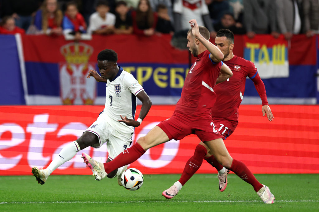 Bukayo Saka of England crosses the ball whilst under pressure from Strahinja Pavlovic and Filip Kostic of Serbia during the UEFA EURO 2024 group st...