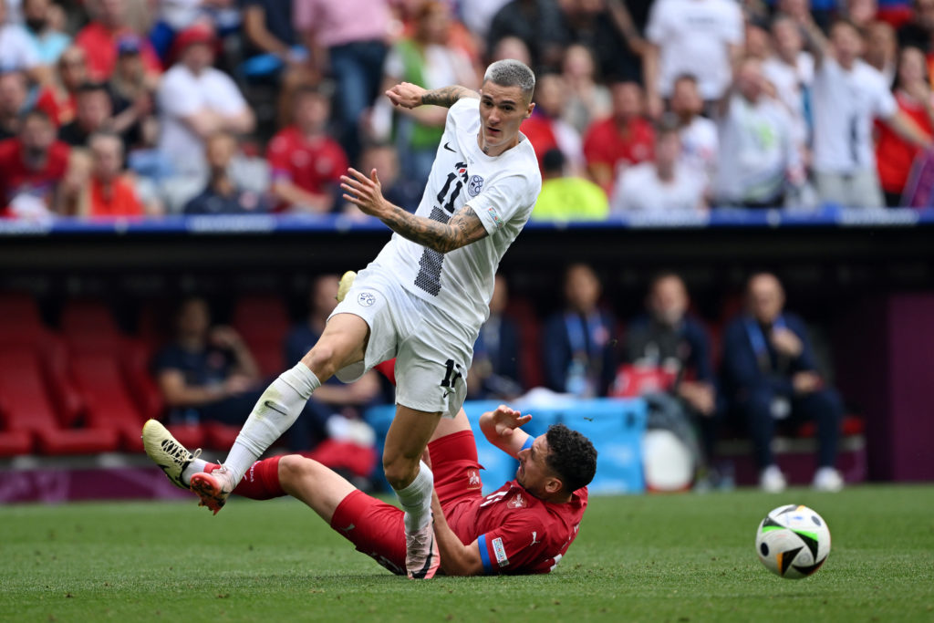 Benjamin Sesko of Slovenia leaps as he avoids a tackle from Milos Veljkovic of Serbia during the UEFA EURO 2024 group stage match between Slovenia ...