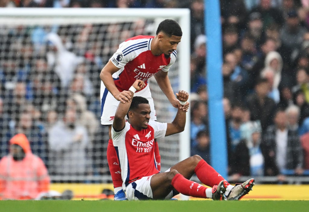 Jurrien Timber of Arsenal is helped up by teammate William Saliba during the Premier League match between Manchester City FC and Arsenal FC at Etih...