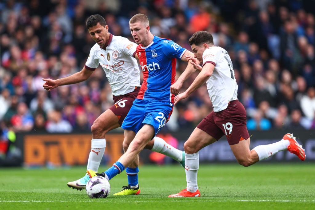 Adam Wharton of Crystal Palace is flanked by Rodri and Julian Alvarez of Manchester City during the Premier League match between Crystal Palace and...