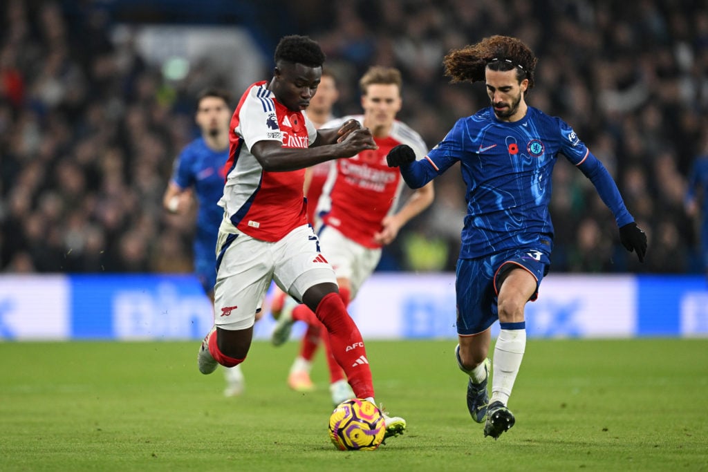 Bukayo Saka of Arsenal runs with the ball whilst under pressure from Marc Cucurella of Chelsea during the Premier League match between Chelsea FC a...