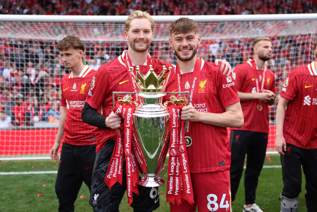 Caoimhin Kelleher poses with the Premier League trophy along with Liverpool teammate Conor Bradley
