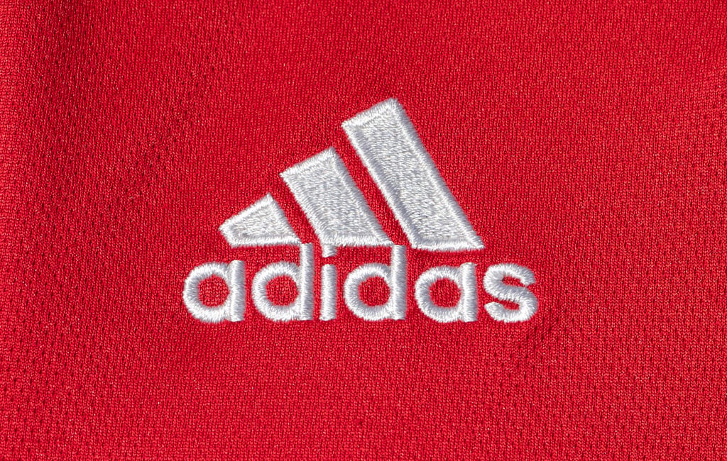 A closeup shot of the Adidas logo on a red background