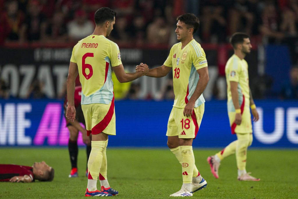 Martin Zubimendi shakes Mikel Merino's hand during a Spain match.