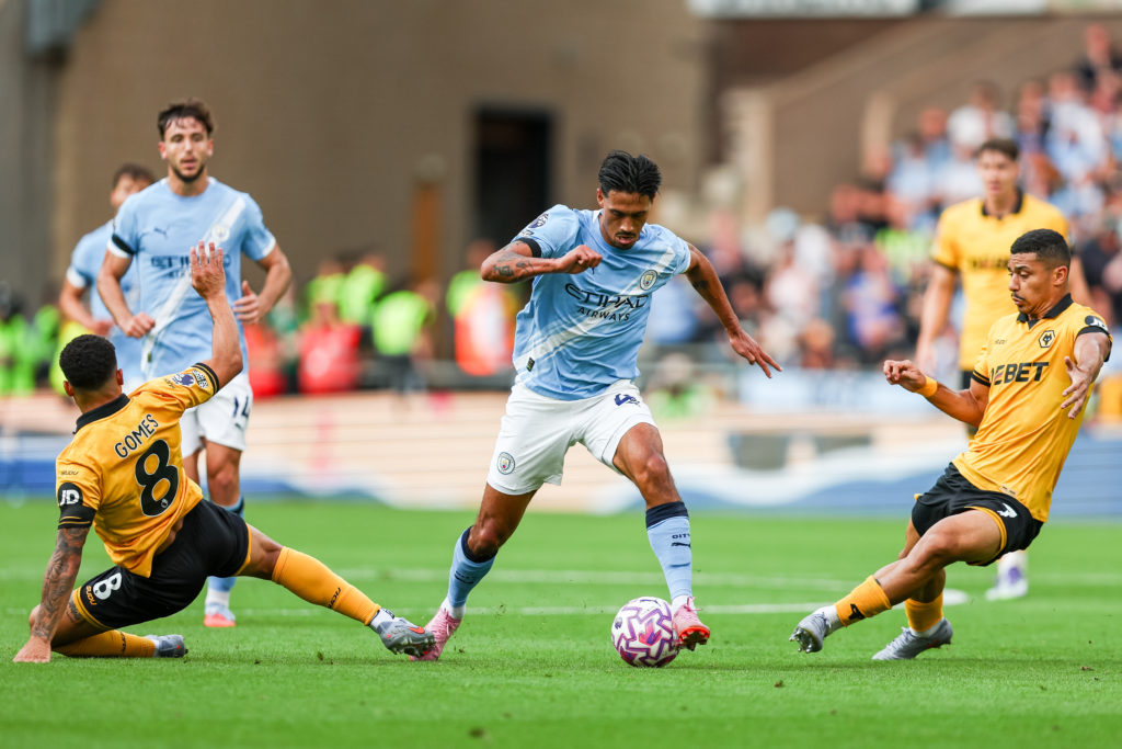 Tijjani Reijnders of Manchester City takes on Joao Gomes and Andre of Wolverhampton Wanderers during the Premier League match between Wolverhampton Wanderers and Manchester City at Molineux