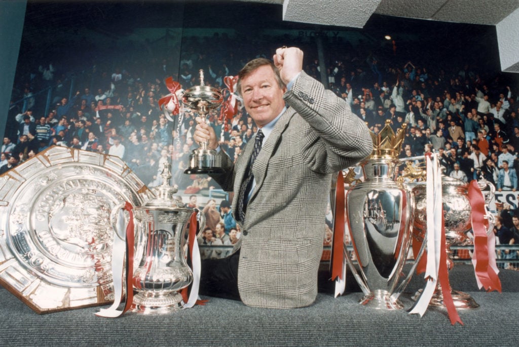 Manchester United manager Sir Alex Ferguson poses with the Premier League, FA Cup, and Community Shield trophies