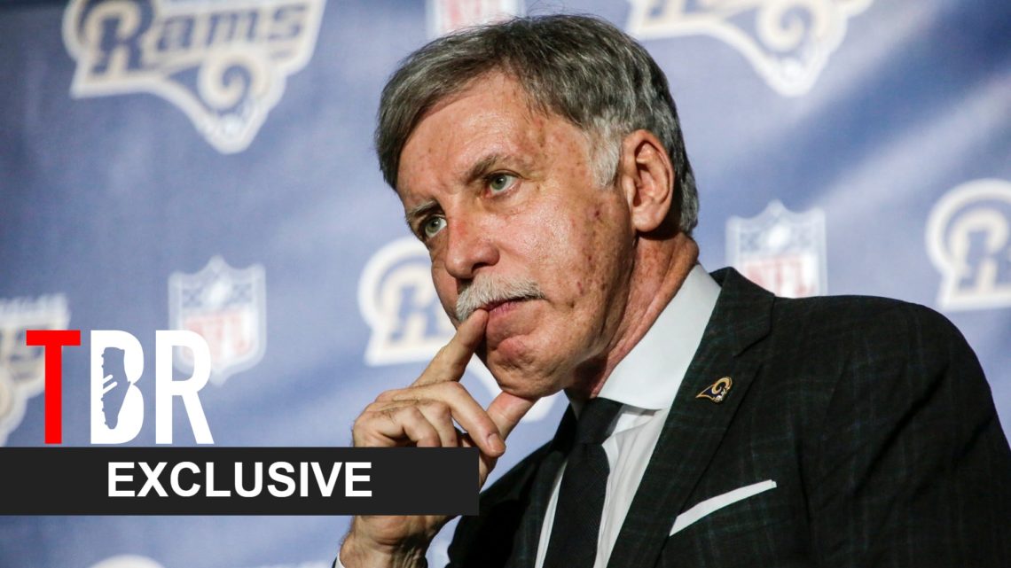 Image of Arsenal owner Stan Kroenke looking on at a press conference in Los Angeles, overlaid a TBR Exclusive banner
