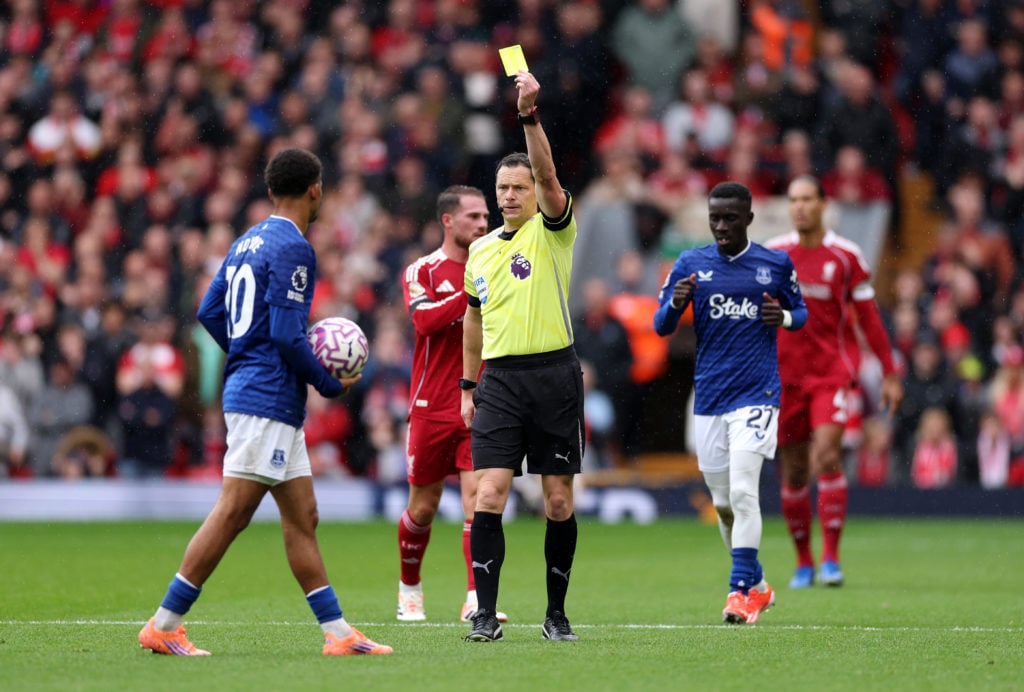 Referee Darren England shows a yellow card to Iliman Ndiaye of Everton during the Premier League match between Liverpool and Everton