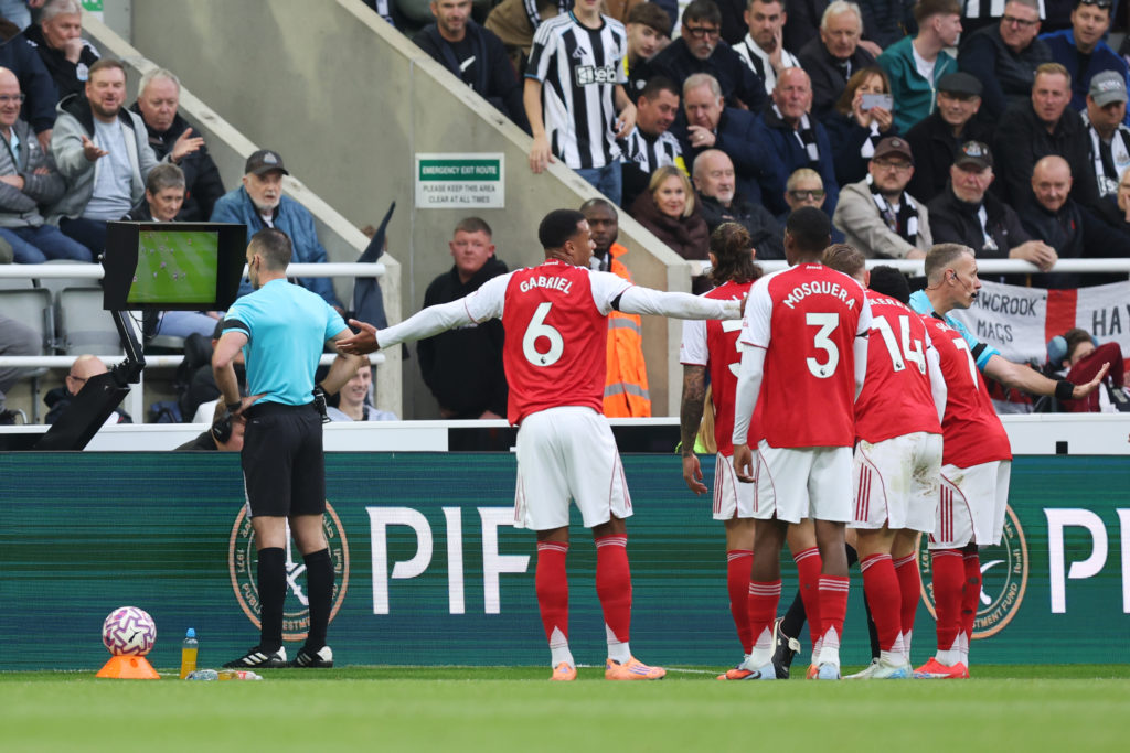 Arsenal players gesture as referee Jarred Gillett checks the VAR pitchside monitor