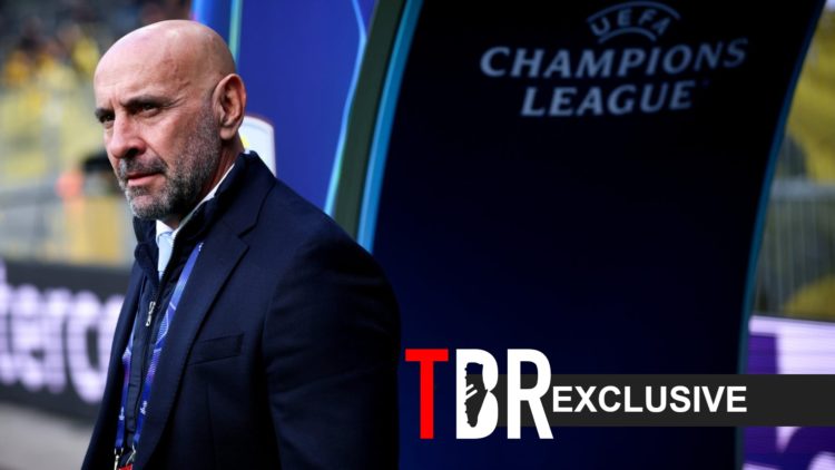 Monchi looks on during an Aston Villa match, alongside a TBR Exclusive banner