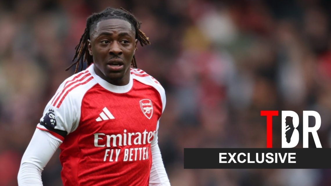 Eberechi Eze looks on during an Arsenal game alongside an exclusive TBR football banner