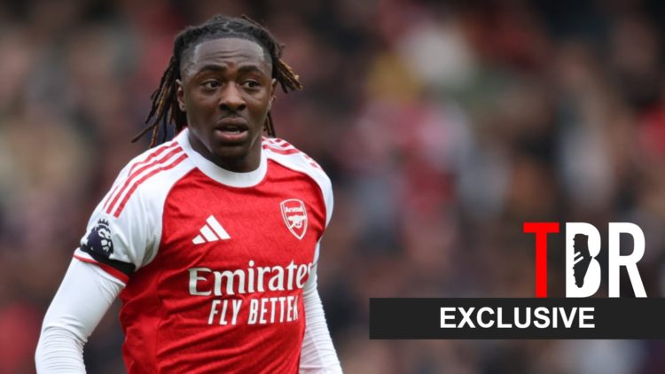 Eberechi Eze looks on during an Arsenal game alongside an exclusive TBR football banner
