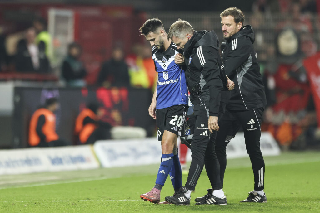 Fabio Vieira is helped off the pitch by Hamburg physios during a match